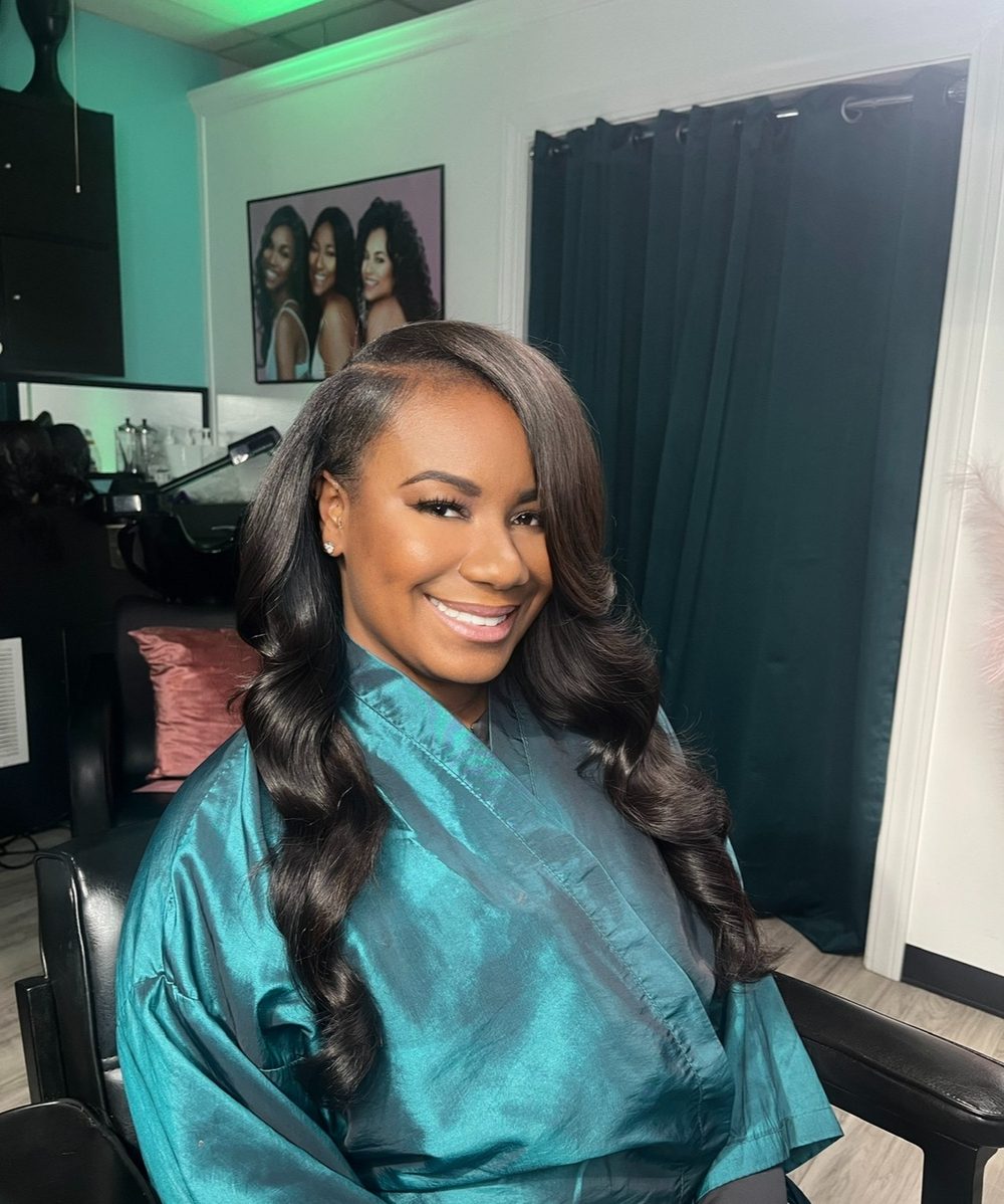 Client sew-in with a side part and long soft waves falling over one shoulder